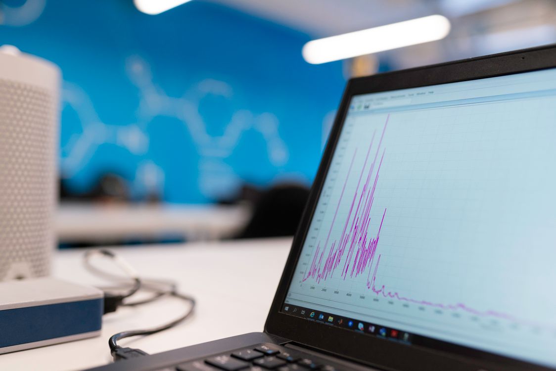 A laptop screen displaying a blue performance analytics graph on a desk in a modern office.